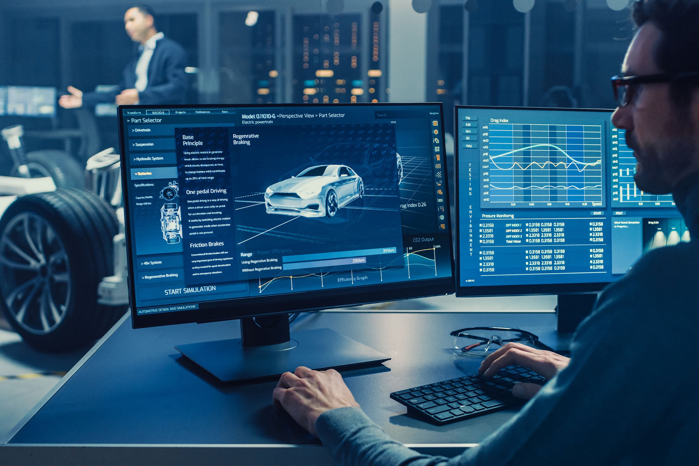 Automotive engineer looking at a computer displaying a 3D electric car chassis prototype with wheels.