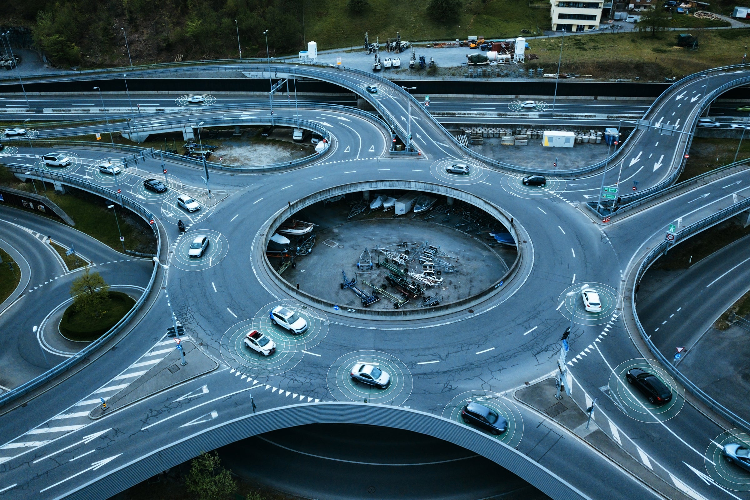 Autonomous self-driving cars moving in a traffic circle next to a highway. 