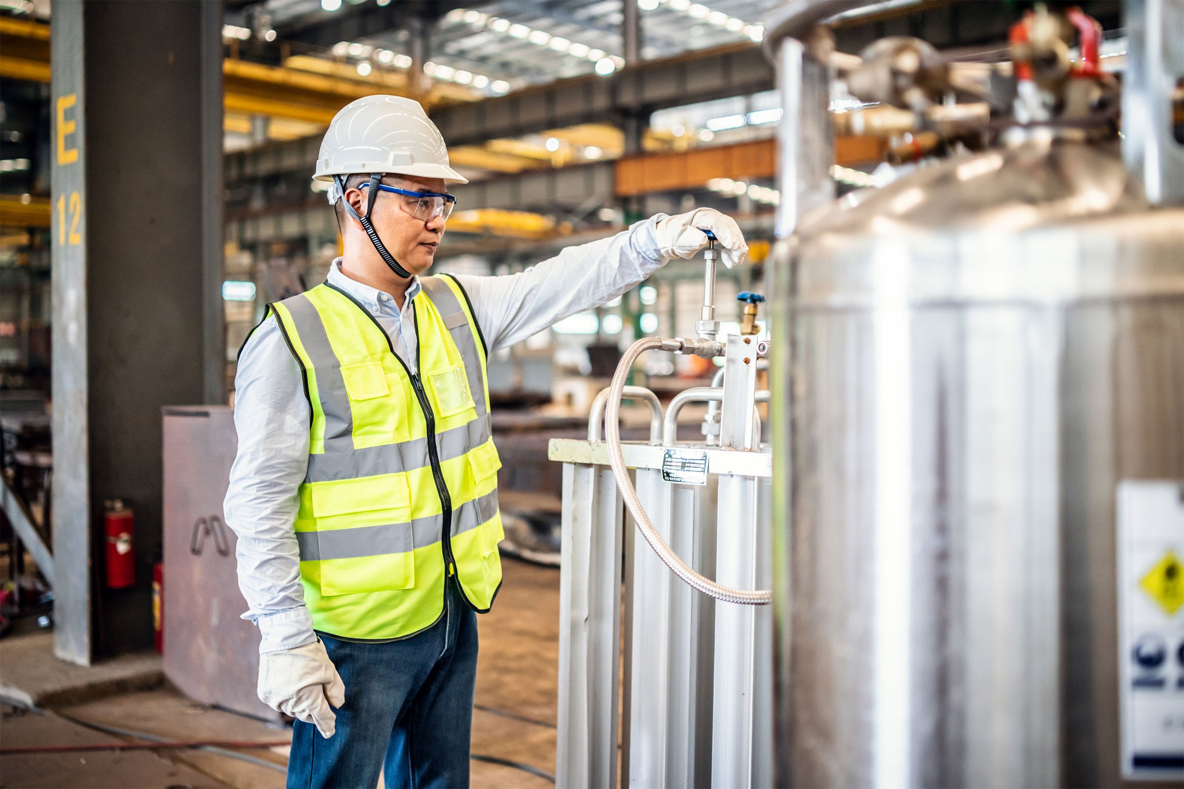 Worker operating a gas tank in a factory.  