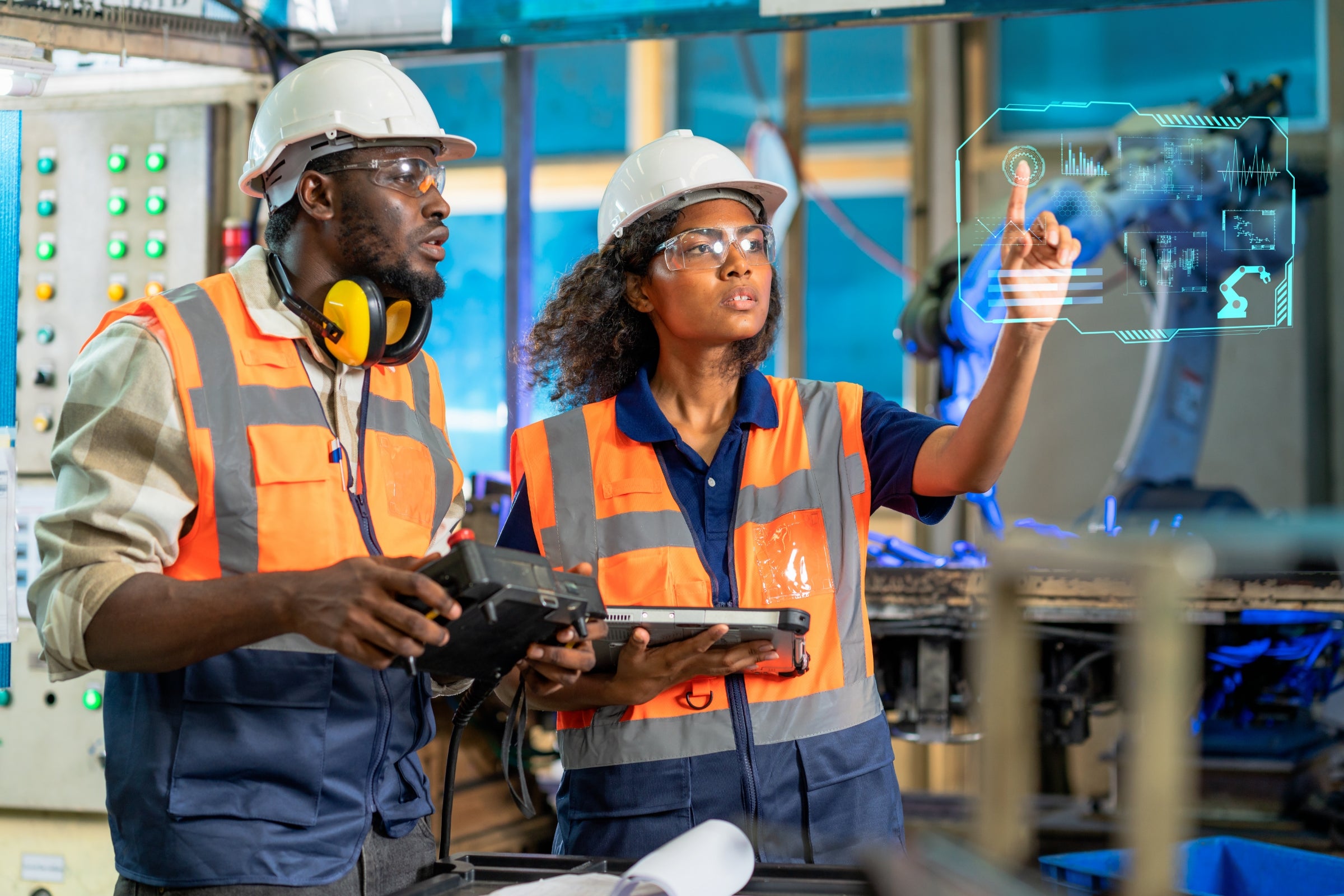 Engineer using tablet to check the robot system while her teamwork checks the security of the robot.