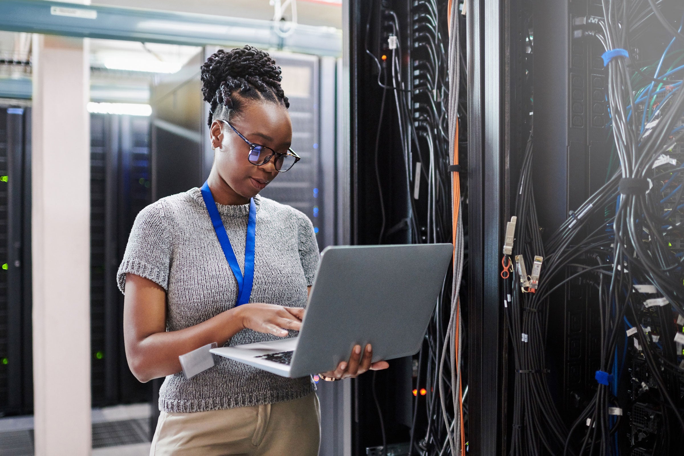Person working on laptop in server room 