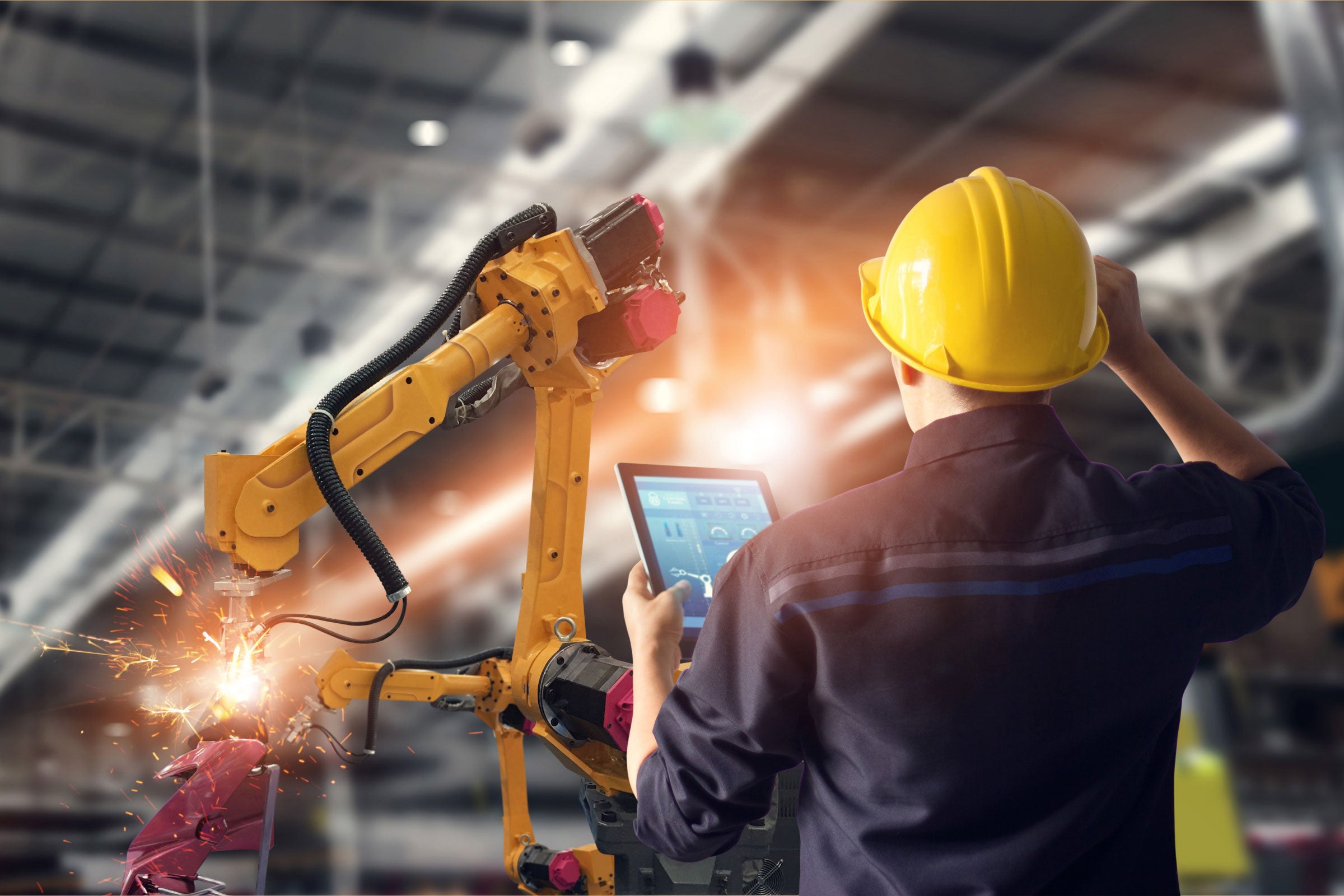 Worker overseeing automated machines in warehouse 