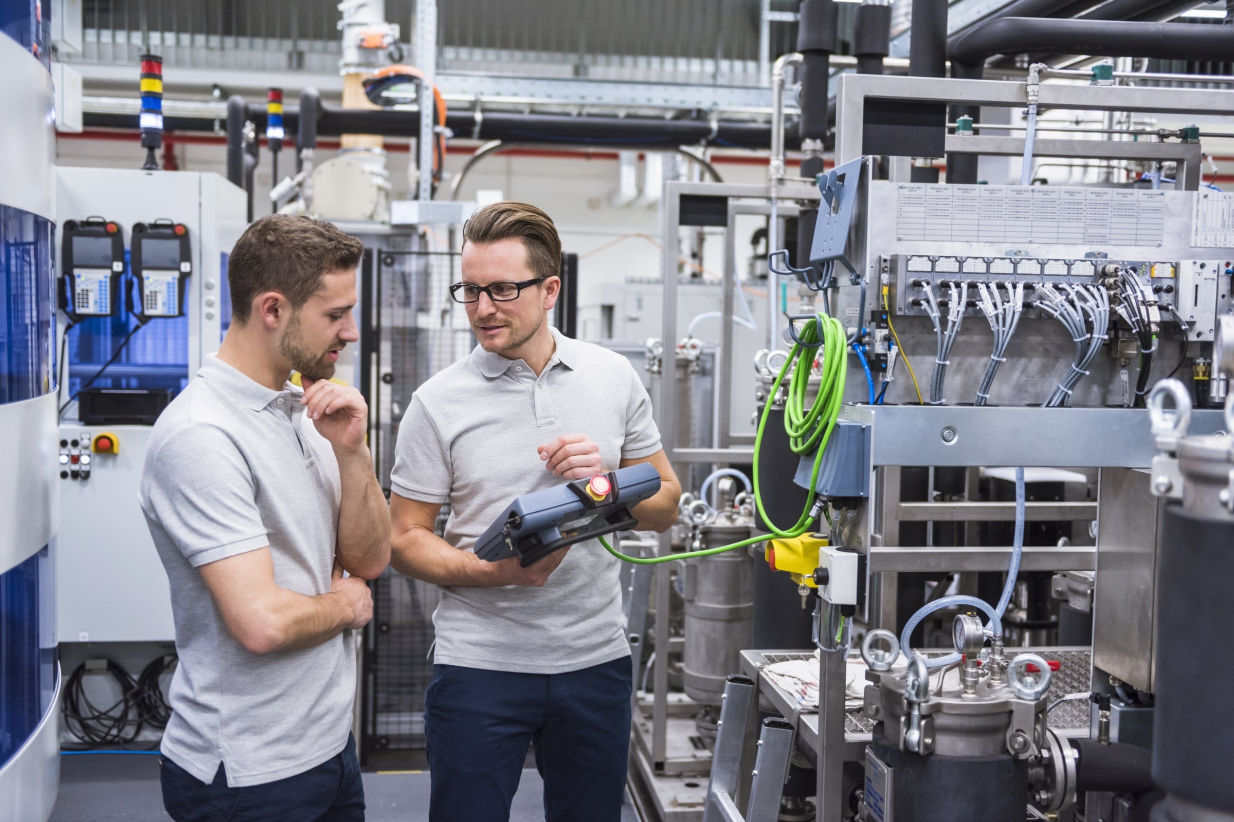 Two men with a control system on factory shop floor.
