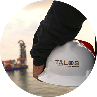 Person holding a white hard hat with the Talos logo on it