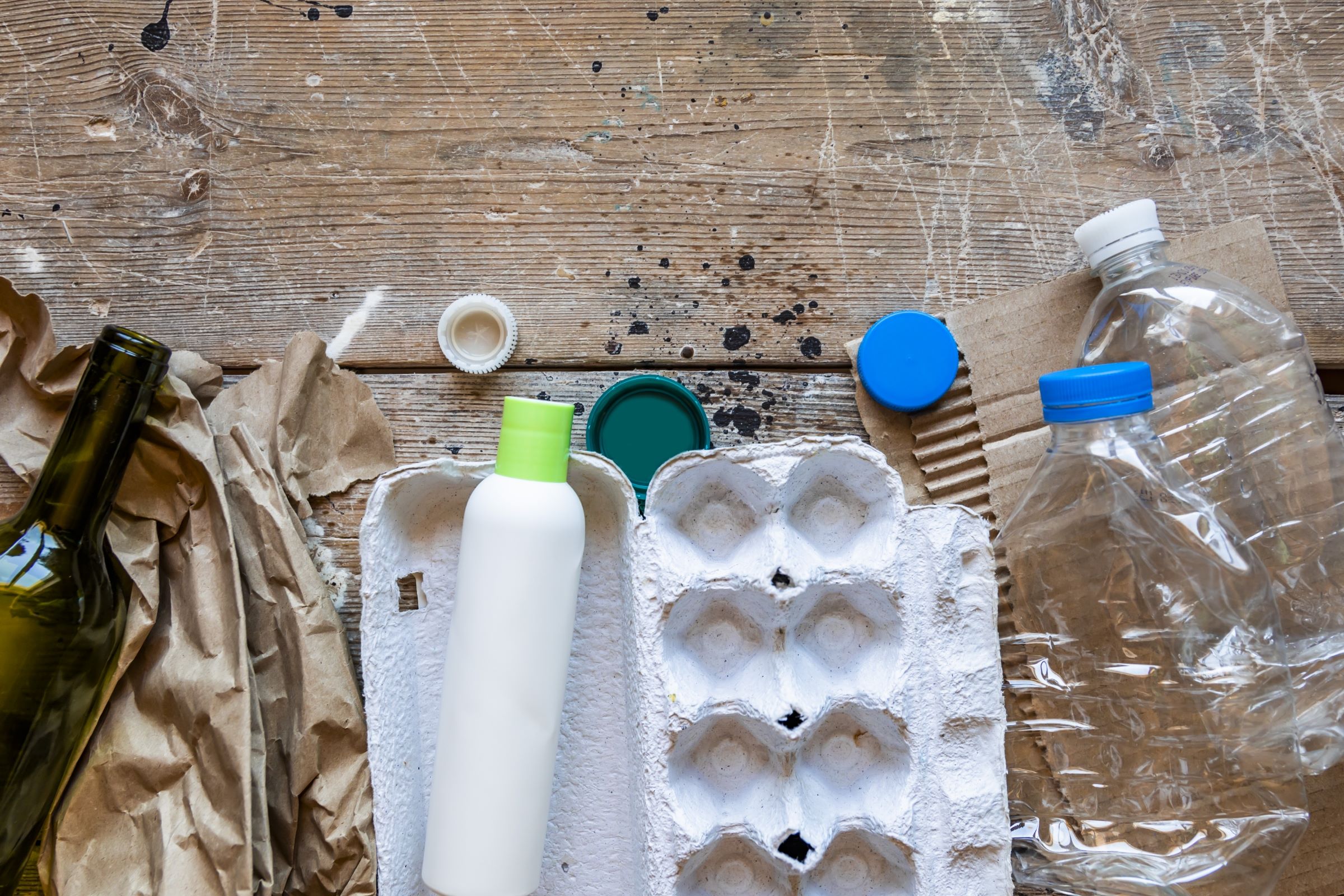 Various types of garbage for recycling on a wooden background.