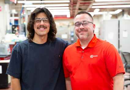 Two people wearing safety glasses smiling together