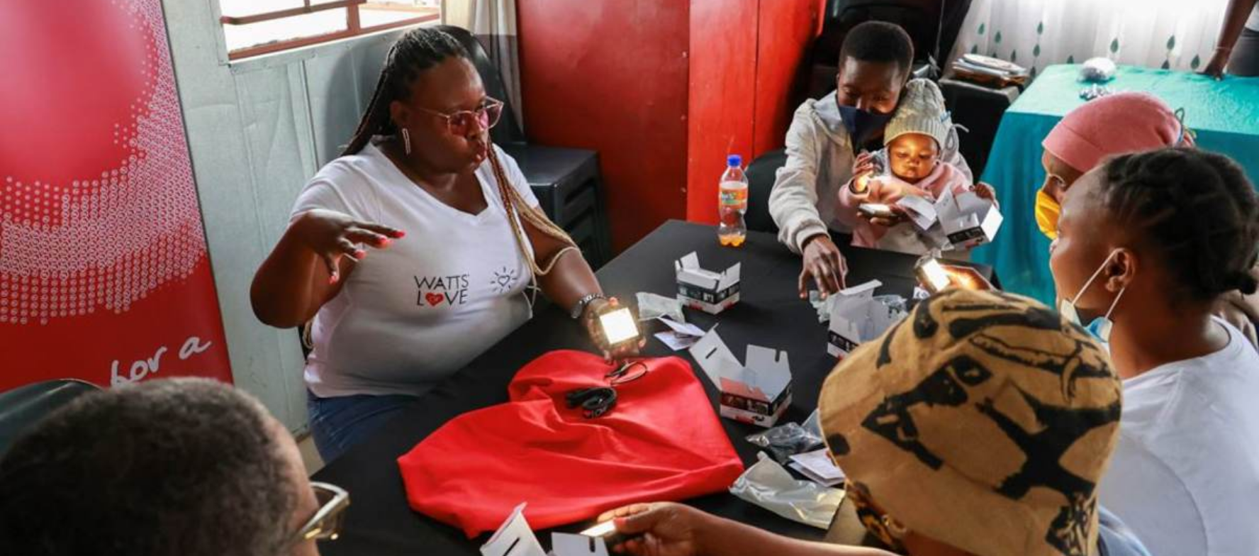 Group of South Africans sit at a table learning how to use their Watts of Love solar-powered lights