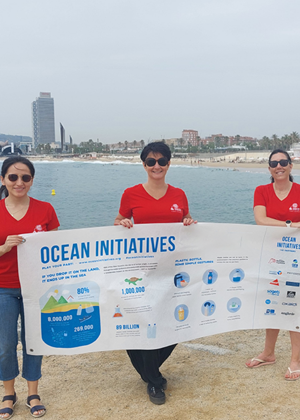 UL Solutions employees holding an "Ocean Initiatives" banner on a beach