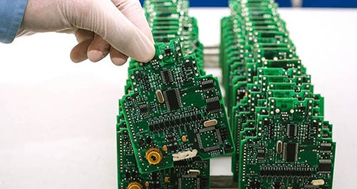 A gloved hand holding a computer board with other boards in the background