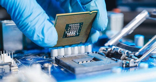 A gloved hand holding a computer chip