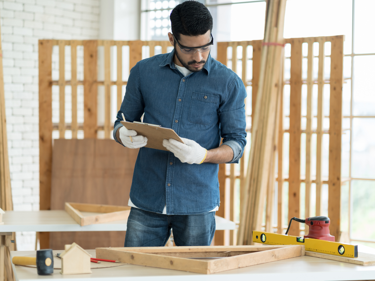 man consulting clipboard in woodshop