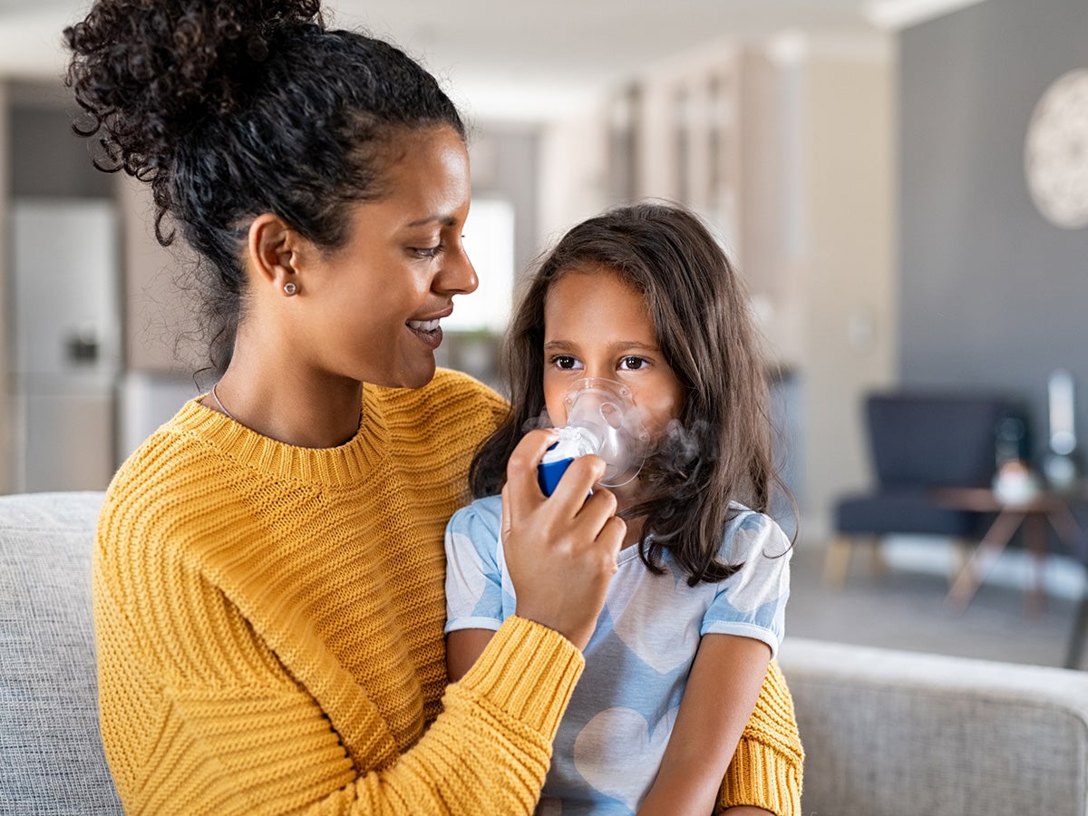 mother helping sick daughter use a nebulizer