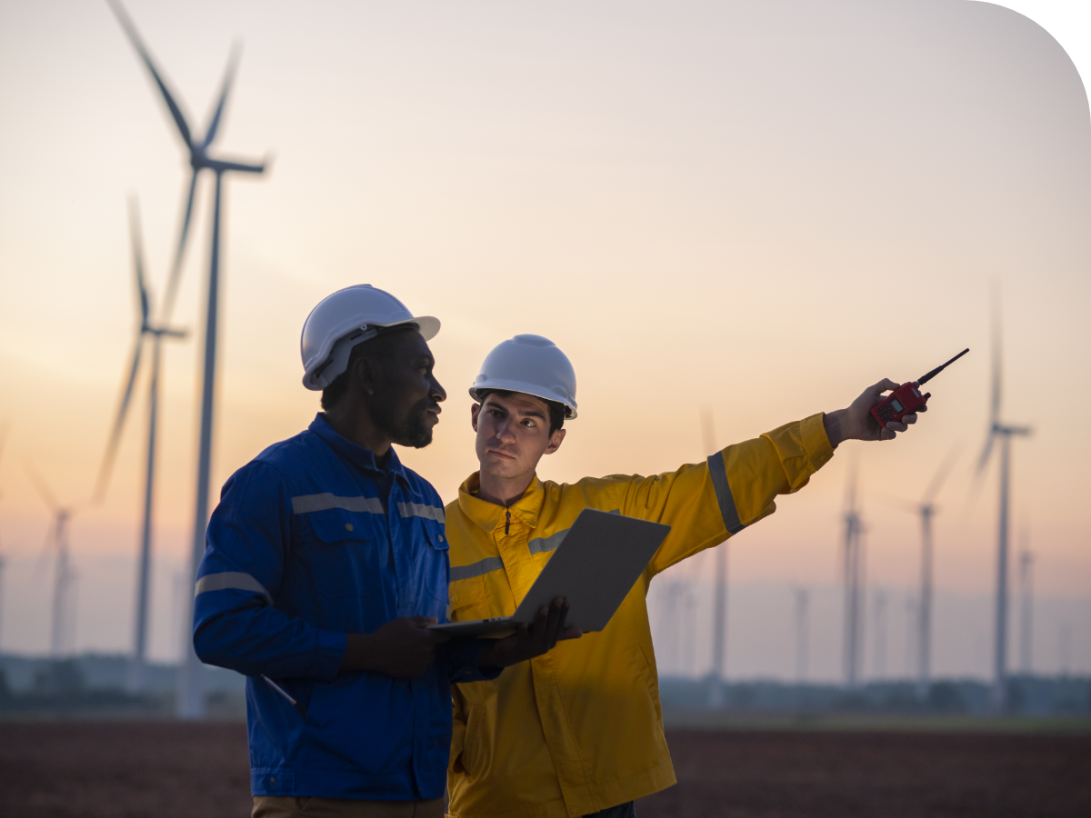Two workers on a wind farm with turbines in the background