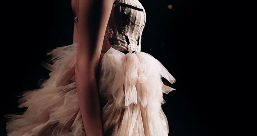 A person wearing a bodice and feathered skirt