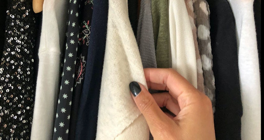 A person's hand thumbing through winter clothes