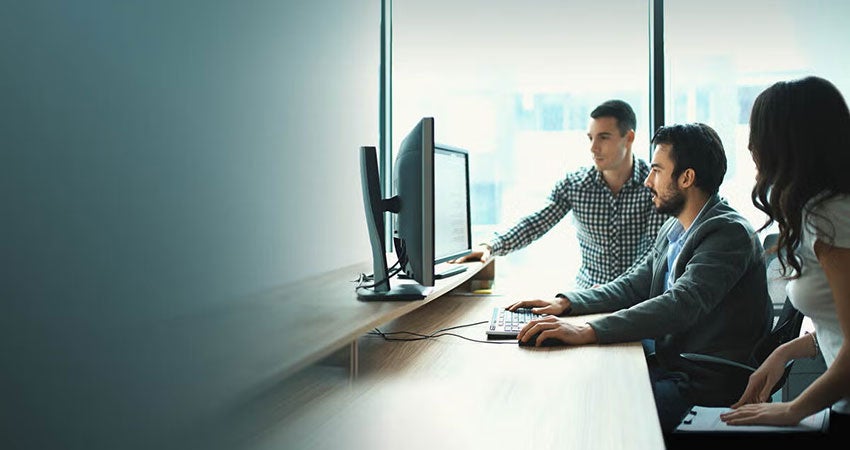 three coworkers reviewing data on a monitor