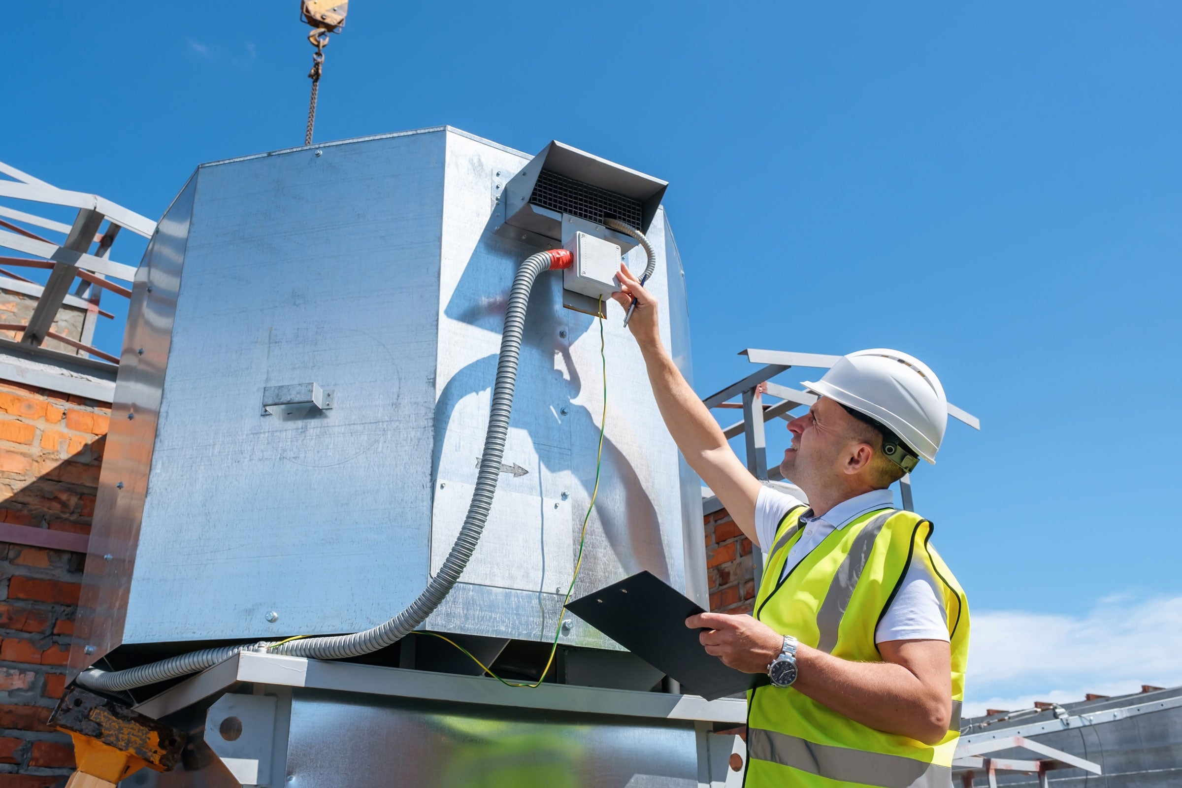 Engineer with clipboard checking the installation of the ventilation system