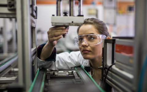 Quality control worker analyzing machine part on a manufacturing machine.