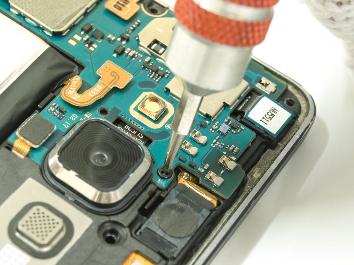 Closeup of a person tightening a screw while repairing a smart phone