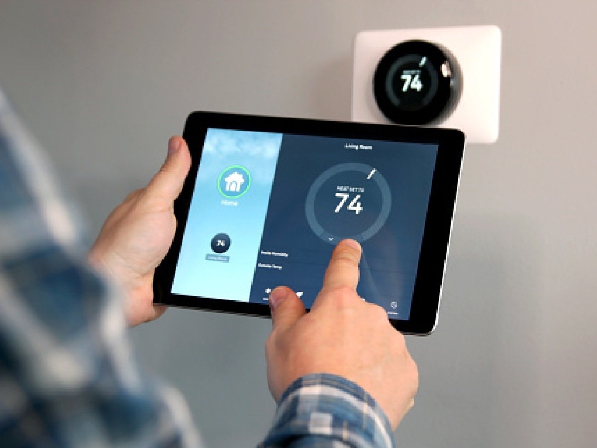 Homeowner adjusting a temperature using a tablet with smart home app in modern living room