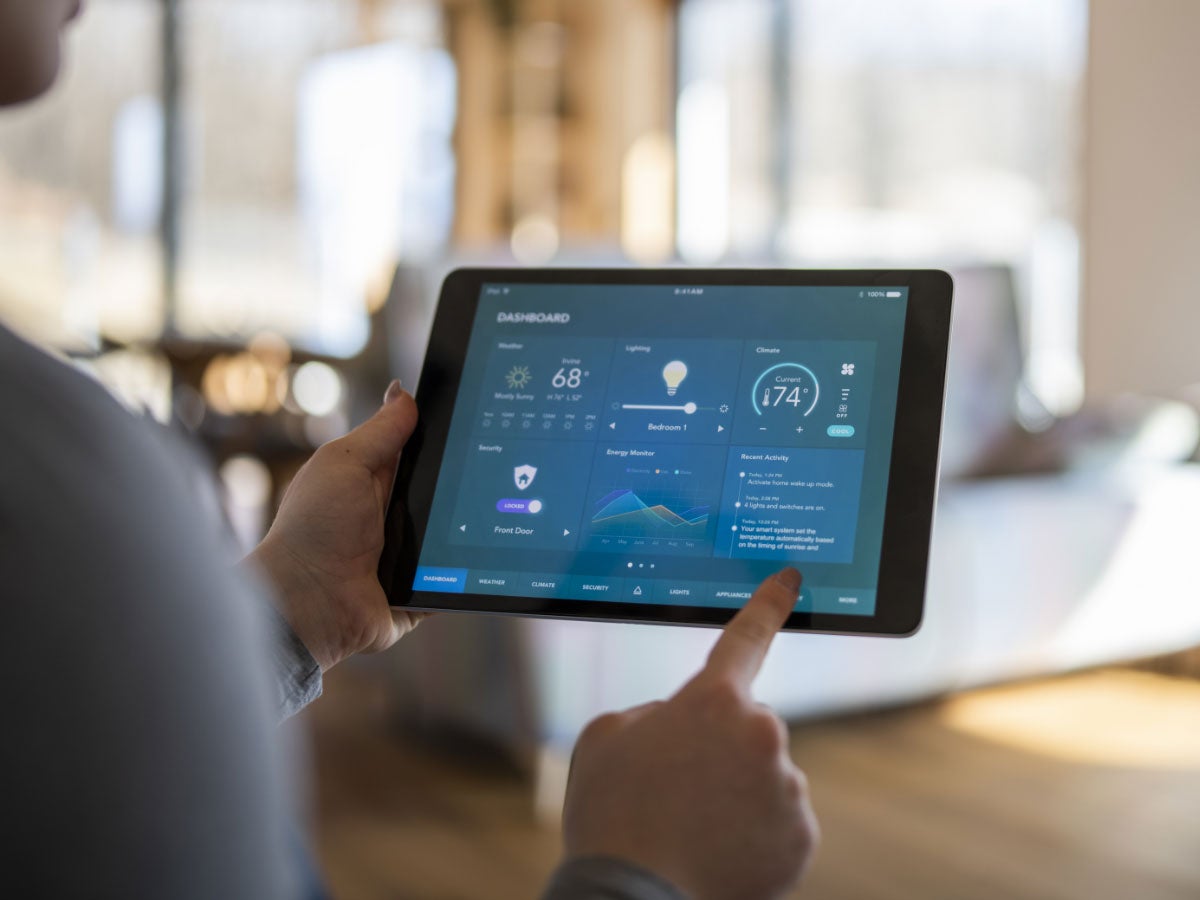 Homeowner using a tablet with smart home control functions to adjust lighting