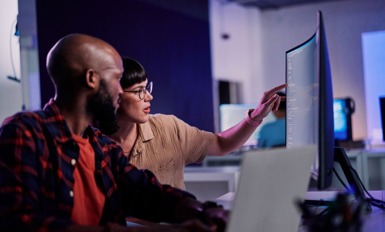 Two developers working together to review software code on a computer