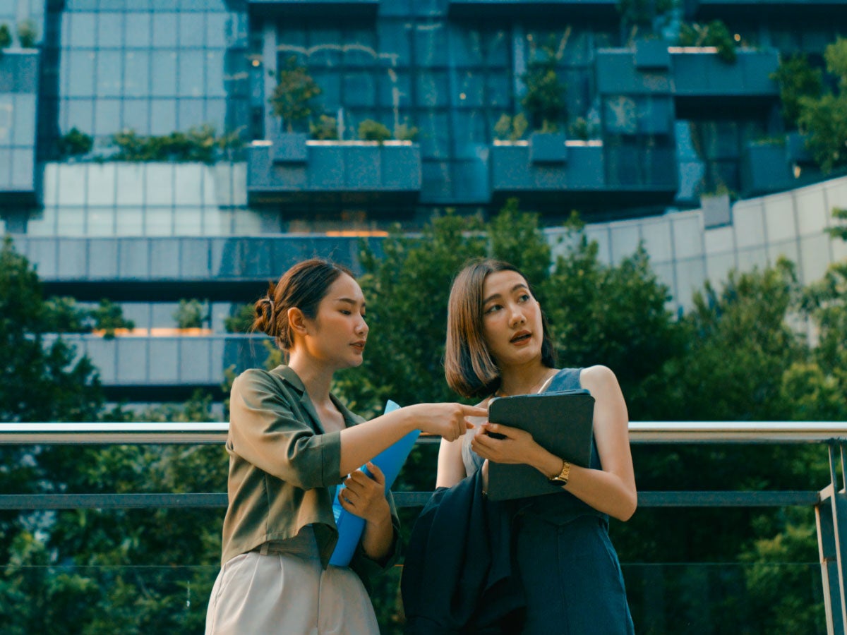 Two business colleagues collaborating over a tablet outside
