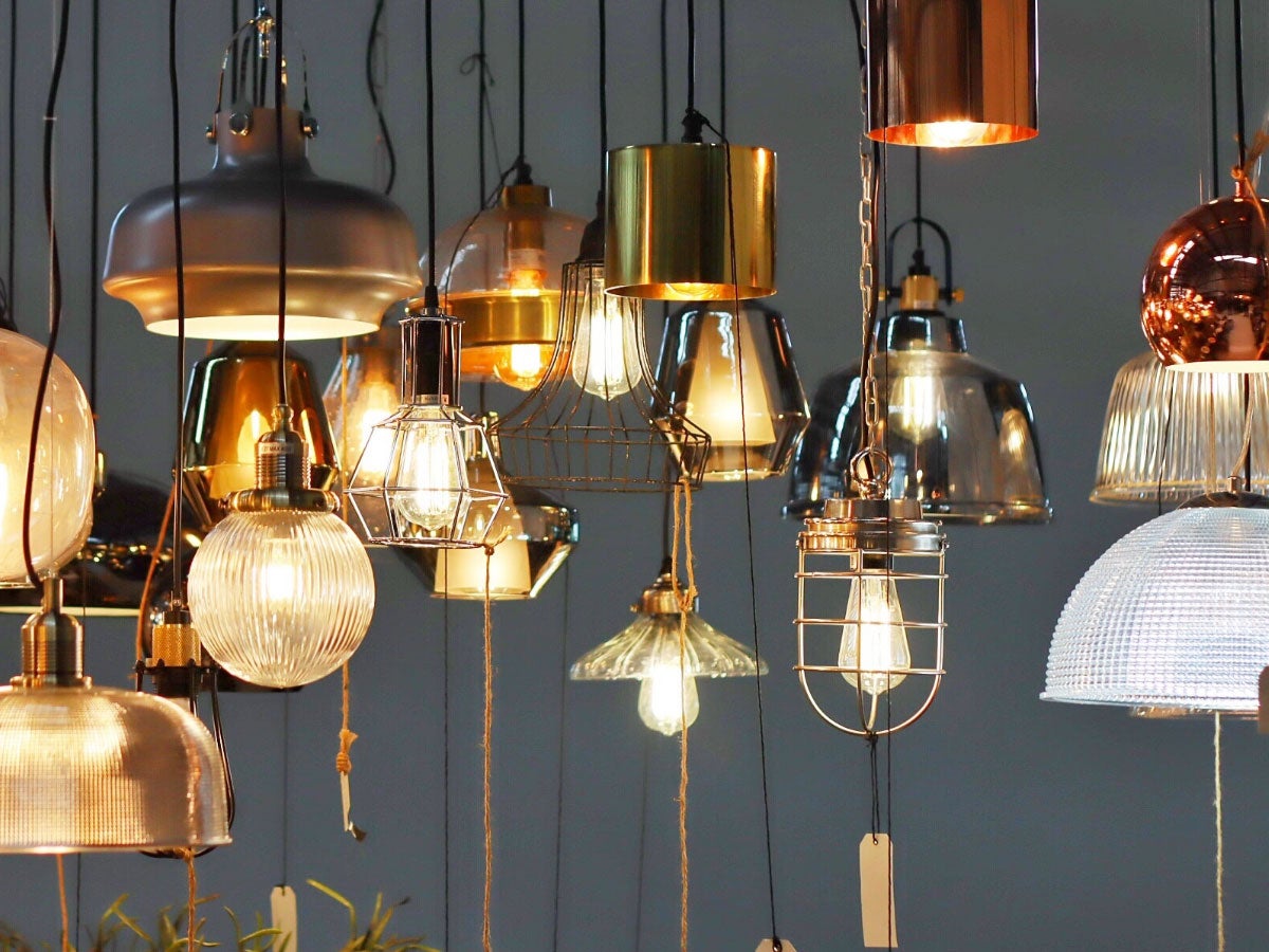 Assorted pendant light fixtures hanging from the ceiling on display in a lighting store.