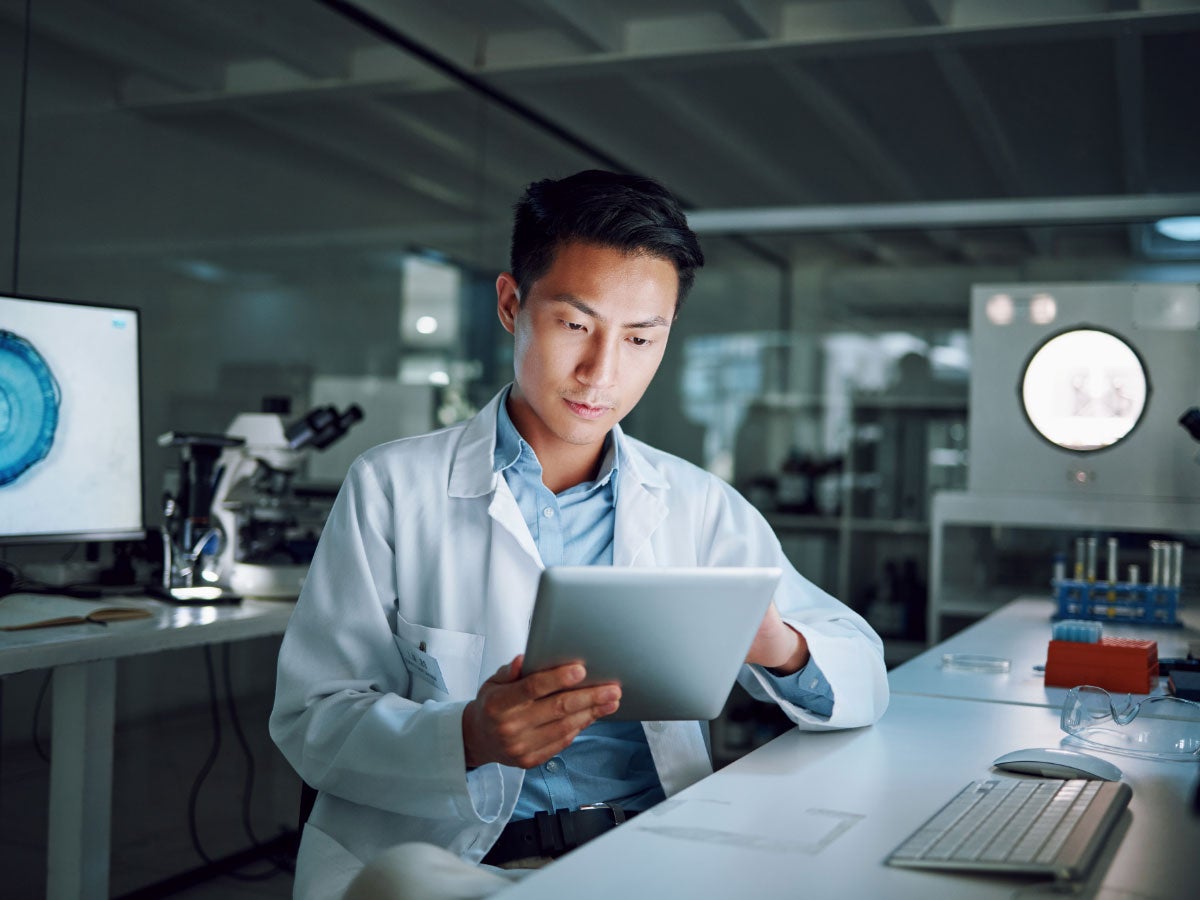 Lab tech reviewing data on a tablet in a lab