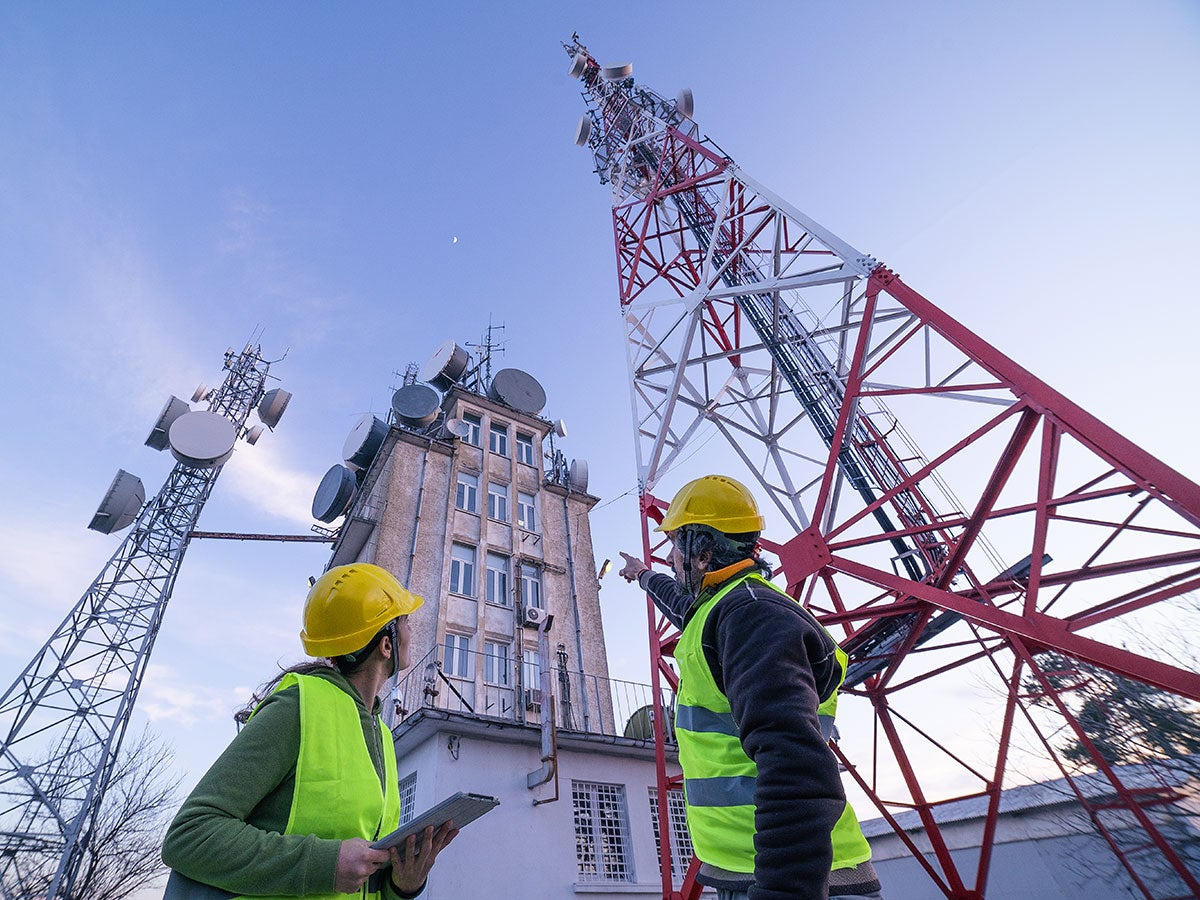 Two engineers looking up at radio towers