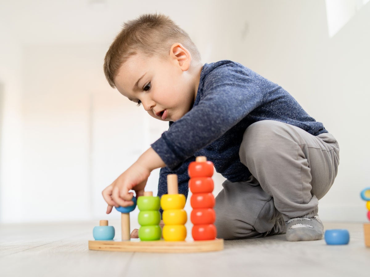 Child playing with little wood toys at home on the floor learning colors and counting