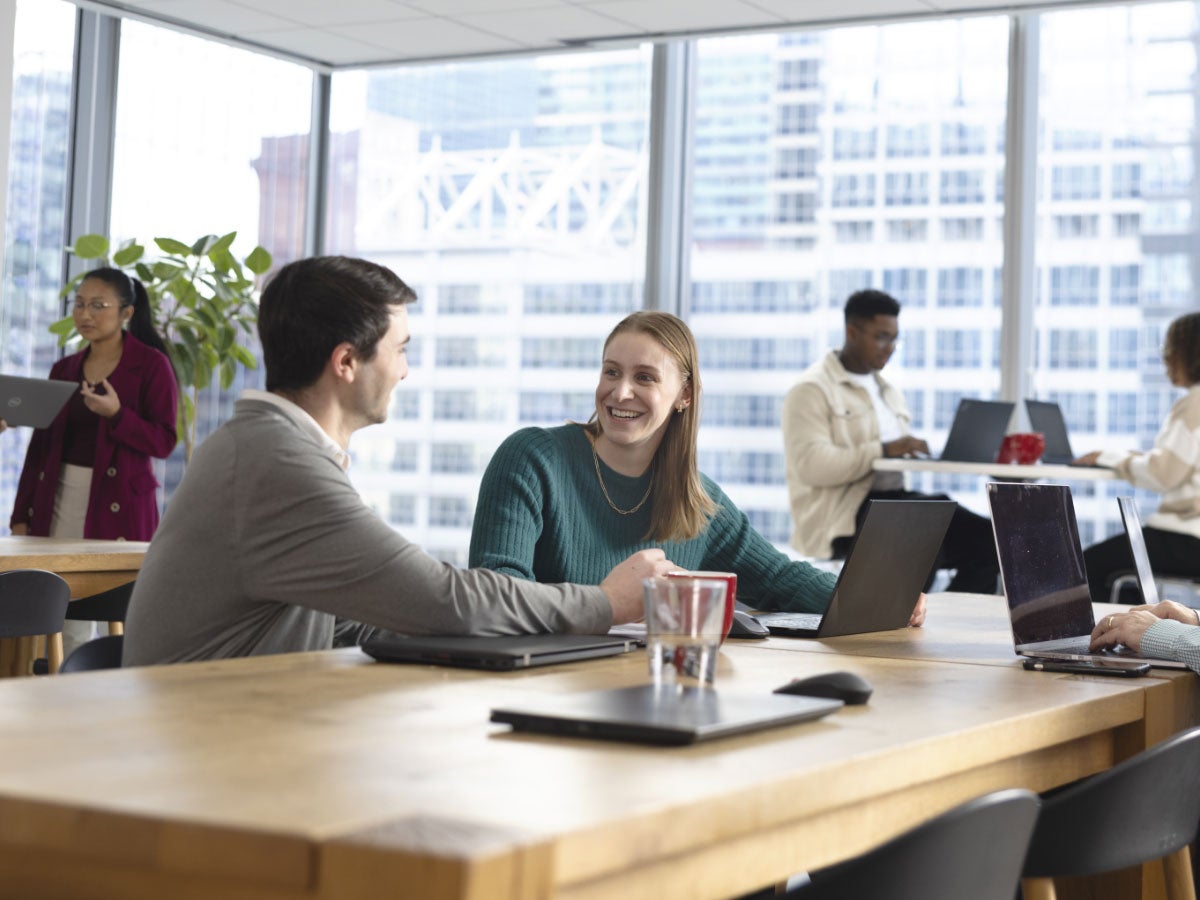 People talking with their laptops in a modern office breakroom