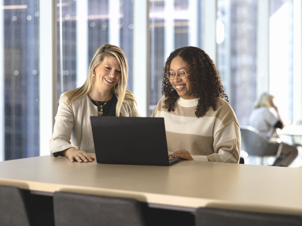 Two colleagues collaborating while looking at a laptop
