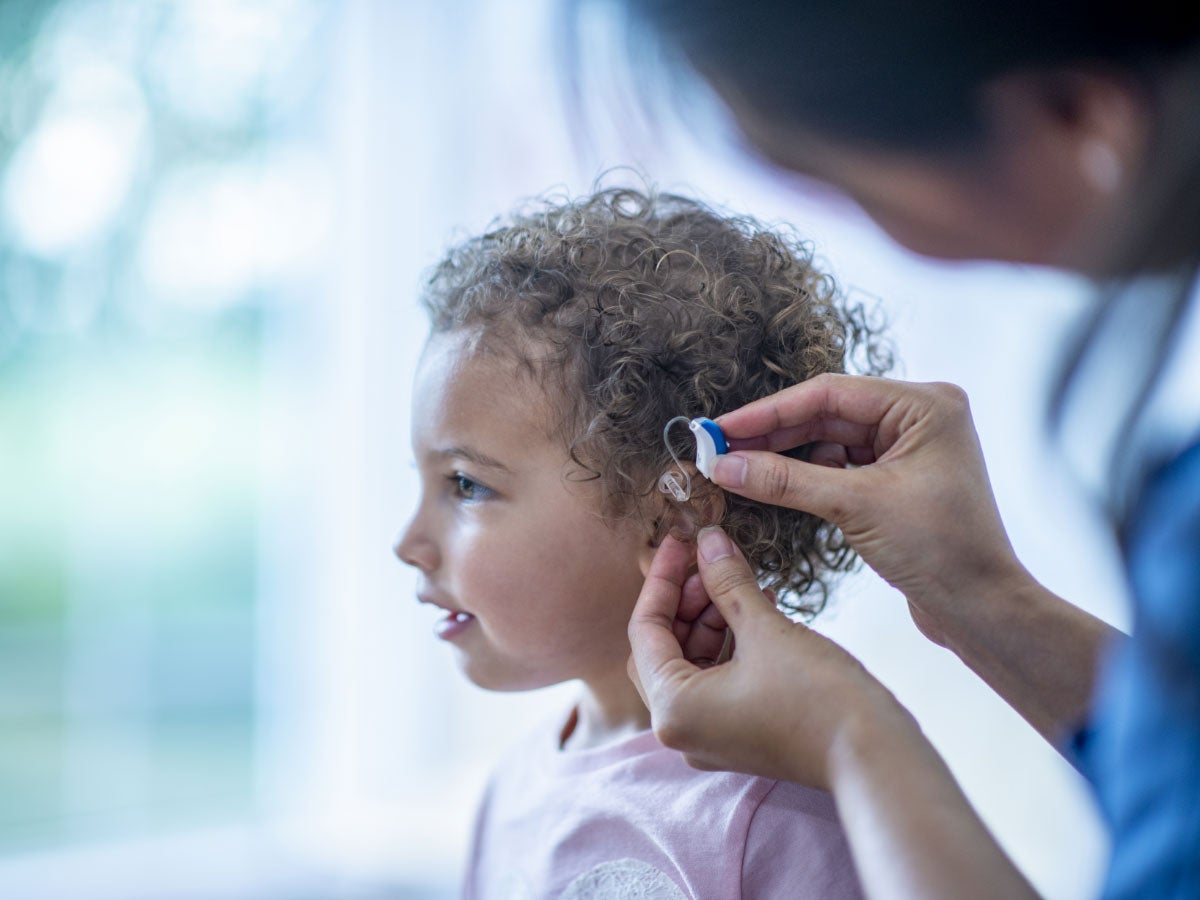 Medical professional adjusting hearing aid for a toddler