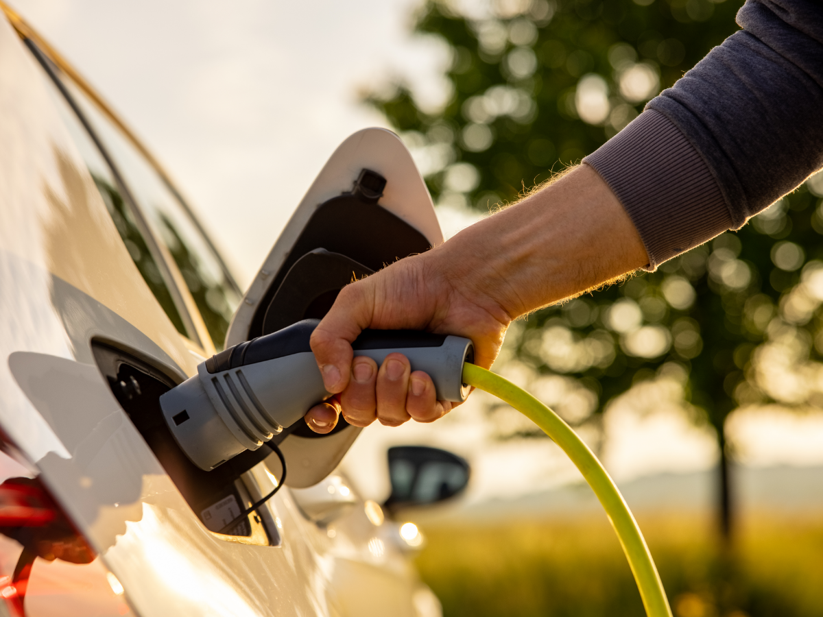 man plugging charger plug into his EV