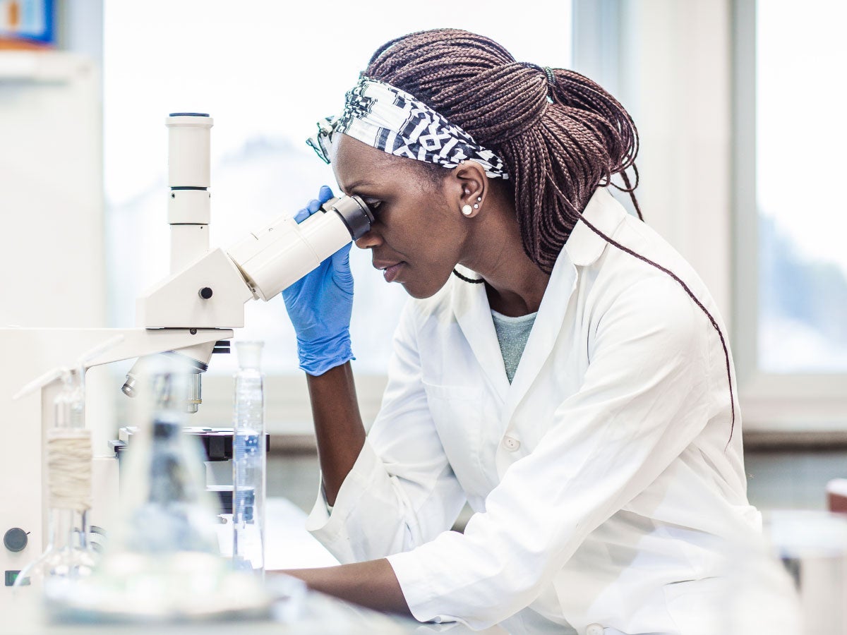 A lab technician looking through a microscope