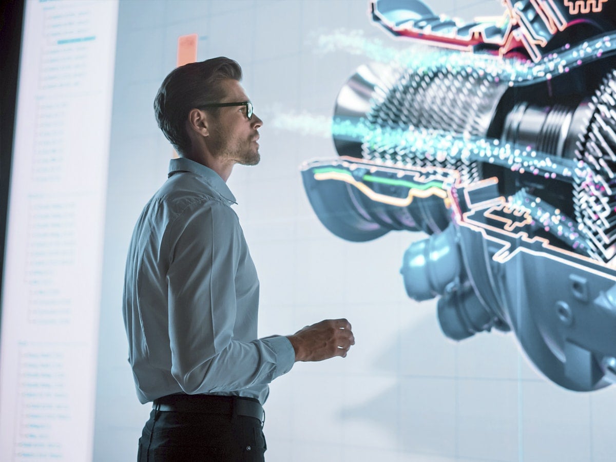 Person viewing a 3D model of an engine on a large display.