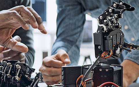 Two people assembling robotic hands in a lab.