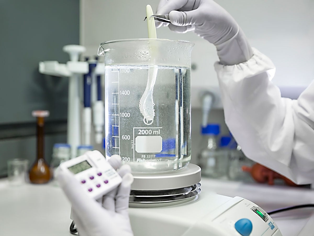 A person measuring a liquid in a laboratory setting