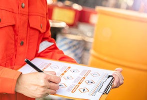 A person inspecting a chemical container and writing a report