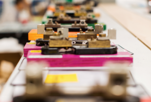 Close-up of multiple metal components aligned on colorful bases in a row