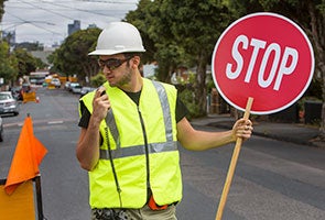 A road worker on a radio and holding a stop sign