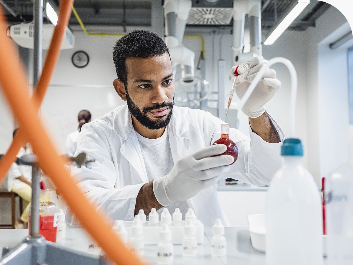 Scientist dropping a chemical into round bottom flask