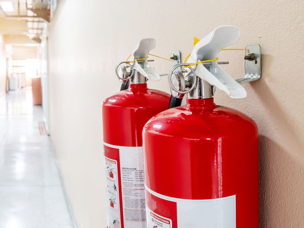 Close-up of two red fire extinguishers hanging on the wall of a hallway