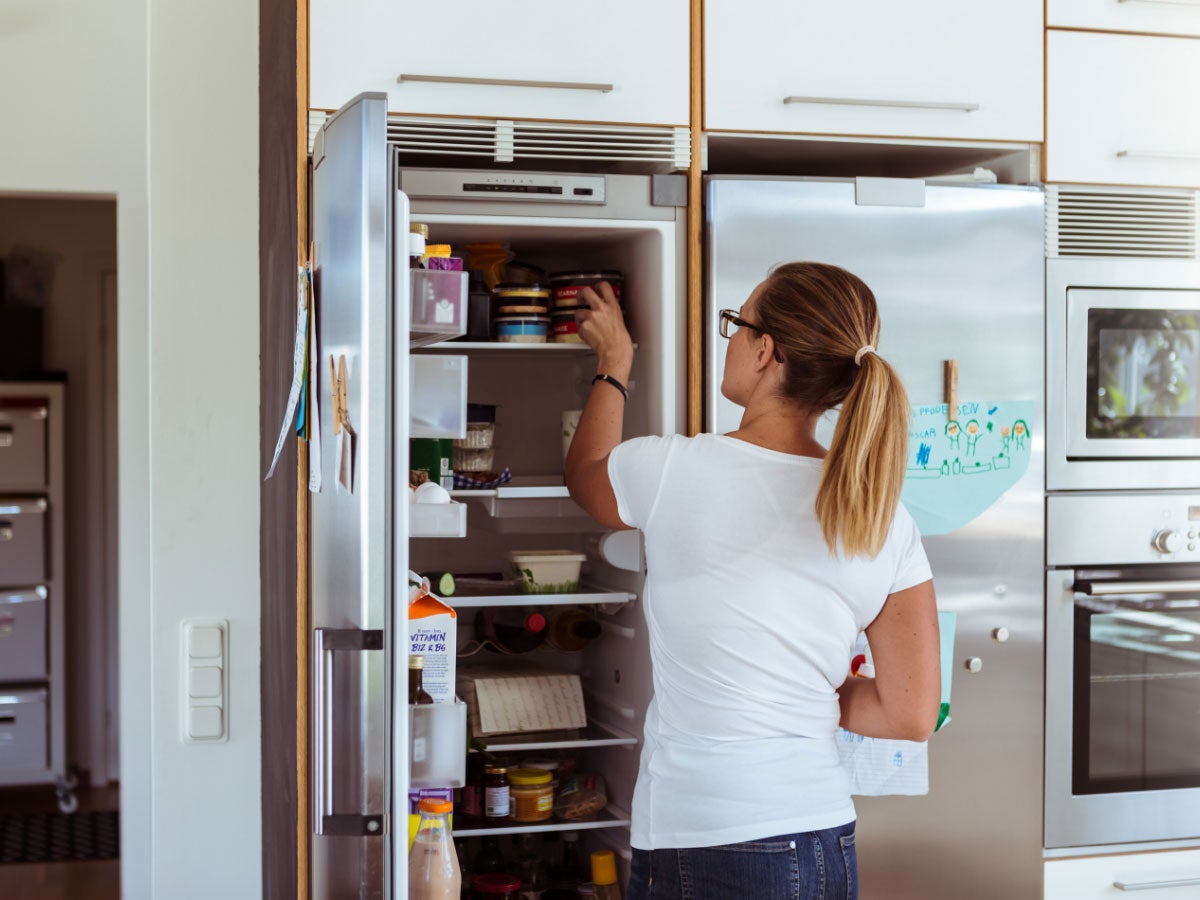 Person looking into the freezer section of a refrigerator in a kitchen 