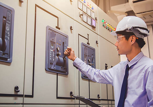 An engineer is checking voltage or current by voltmeter in control panel of power plant