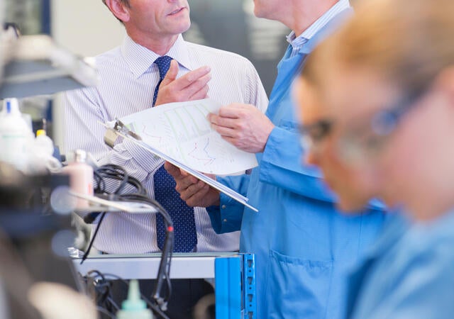 Businessman and engineer talking at production line in circuit board manufacturing plant.
