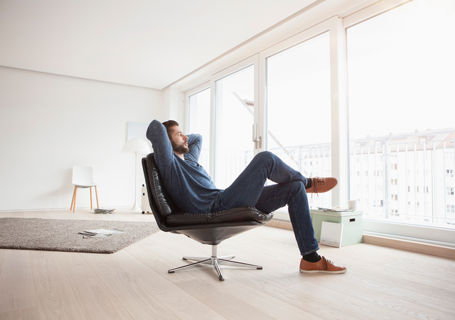 Man relaxing in an armchair conveying a sense of peace of mind, comfort and wellness.