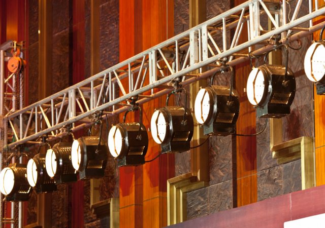 Theater lights hang from backstage scaffolding, ready for the upcoming performance. 