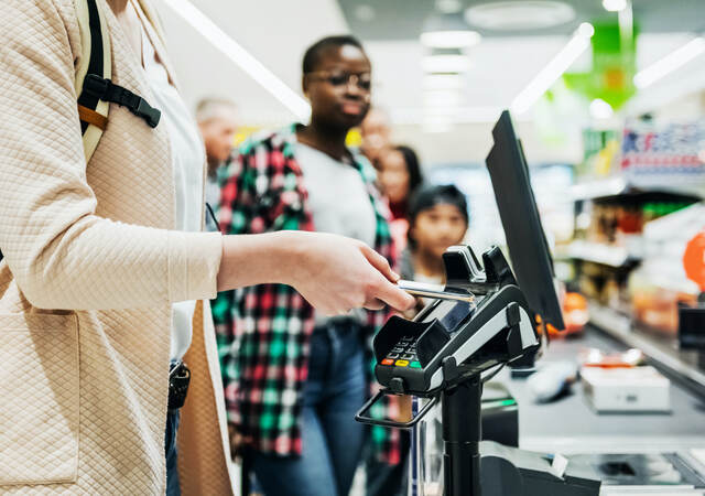woman using a mobile phone to pay for groceries